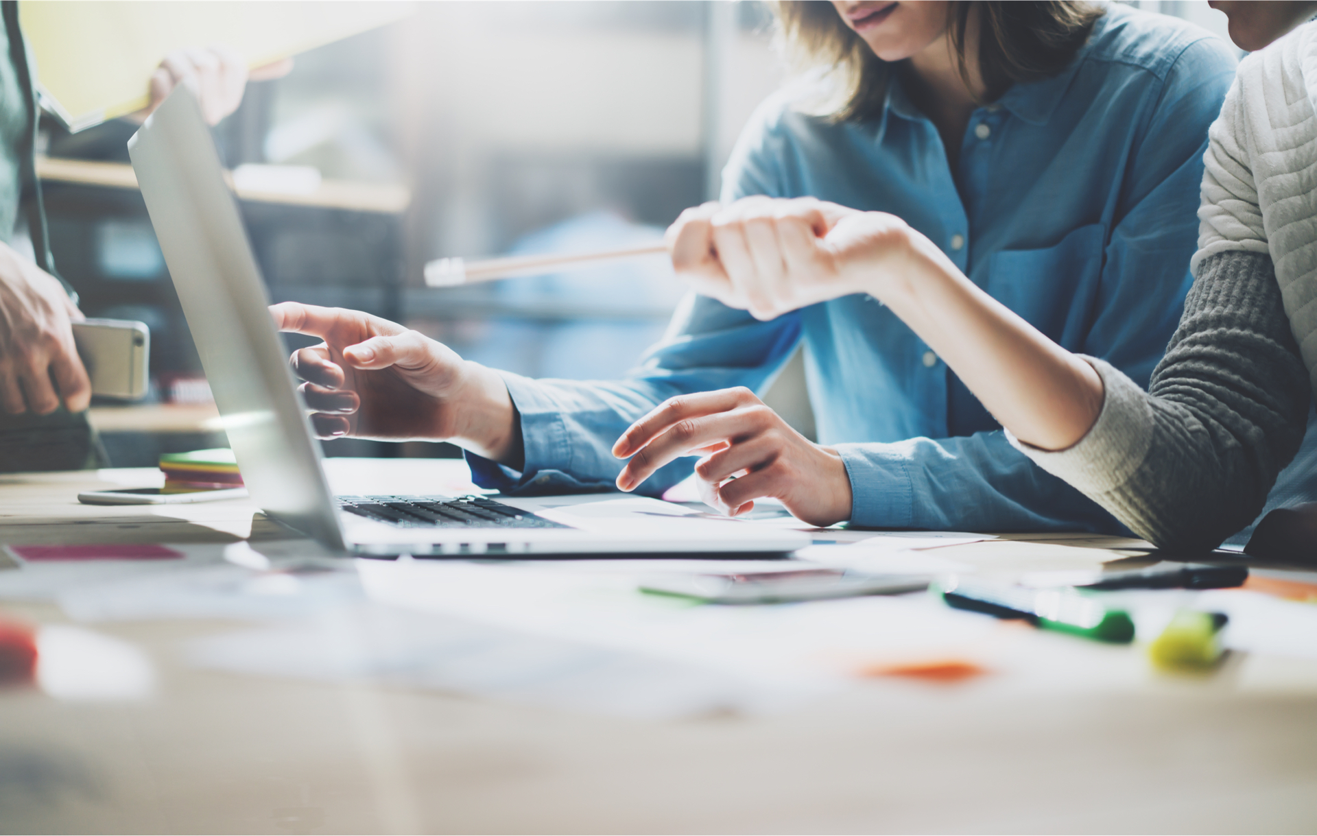 People collaboratively working at desk pointing at laptop screen