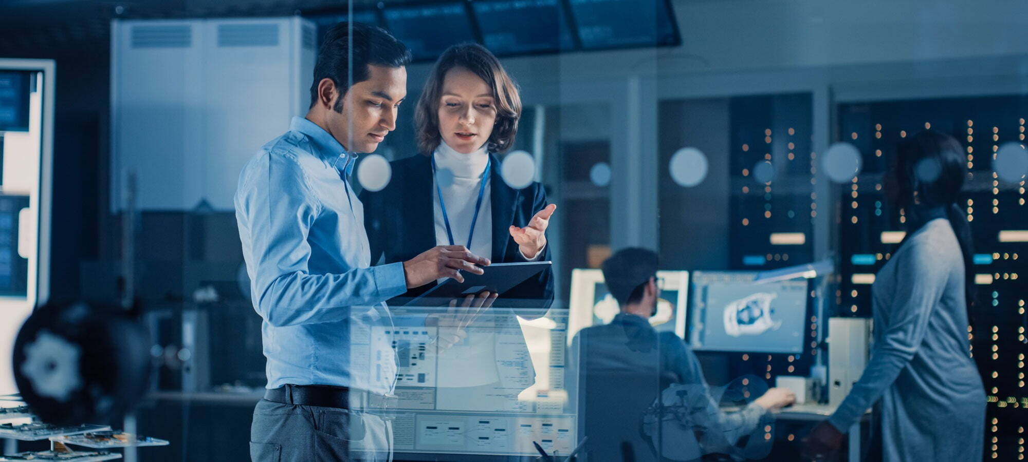 Two people discussing work on tablet within a working environment